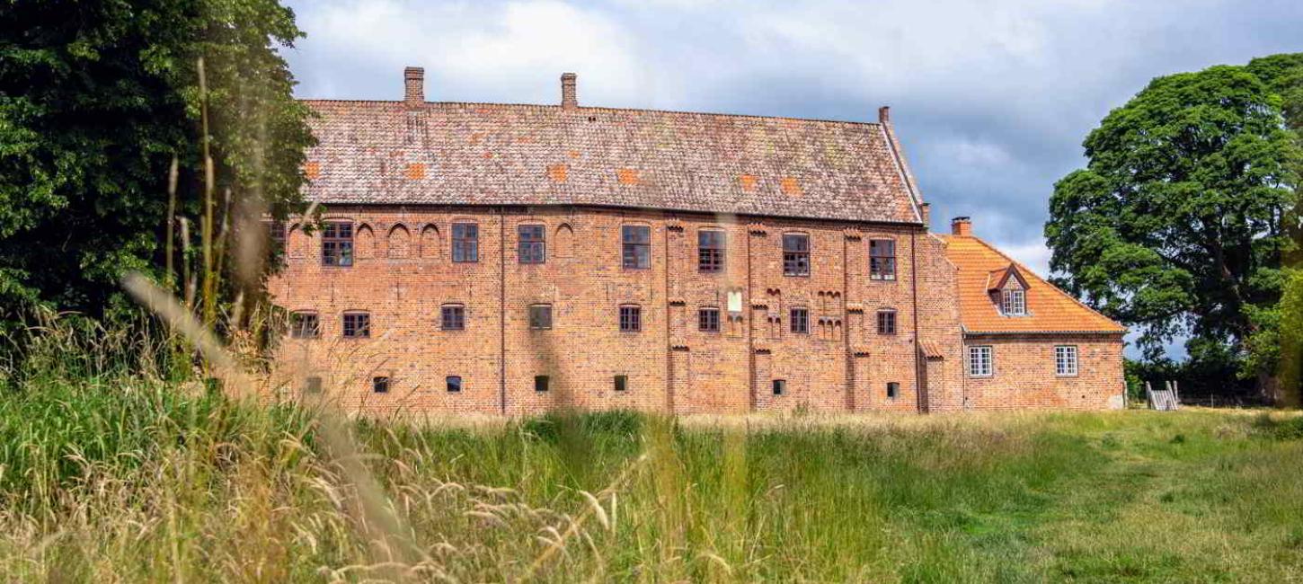 Das rote Ziegelgebäude des Esrum Klosters liegt am Ende einer großen Wiese.