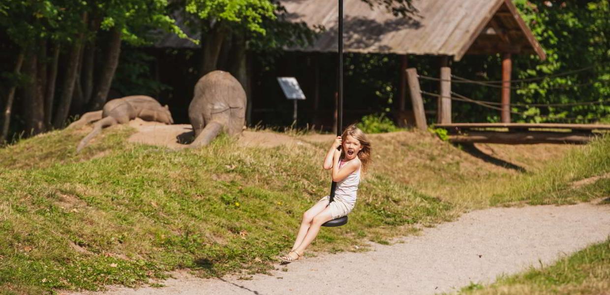 Ein Mädchen lacht, während sie auf der Seilrutsche auf dem Natur-Spielplatz des Esrum Klosters davonfliegt.