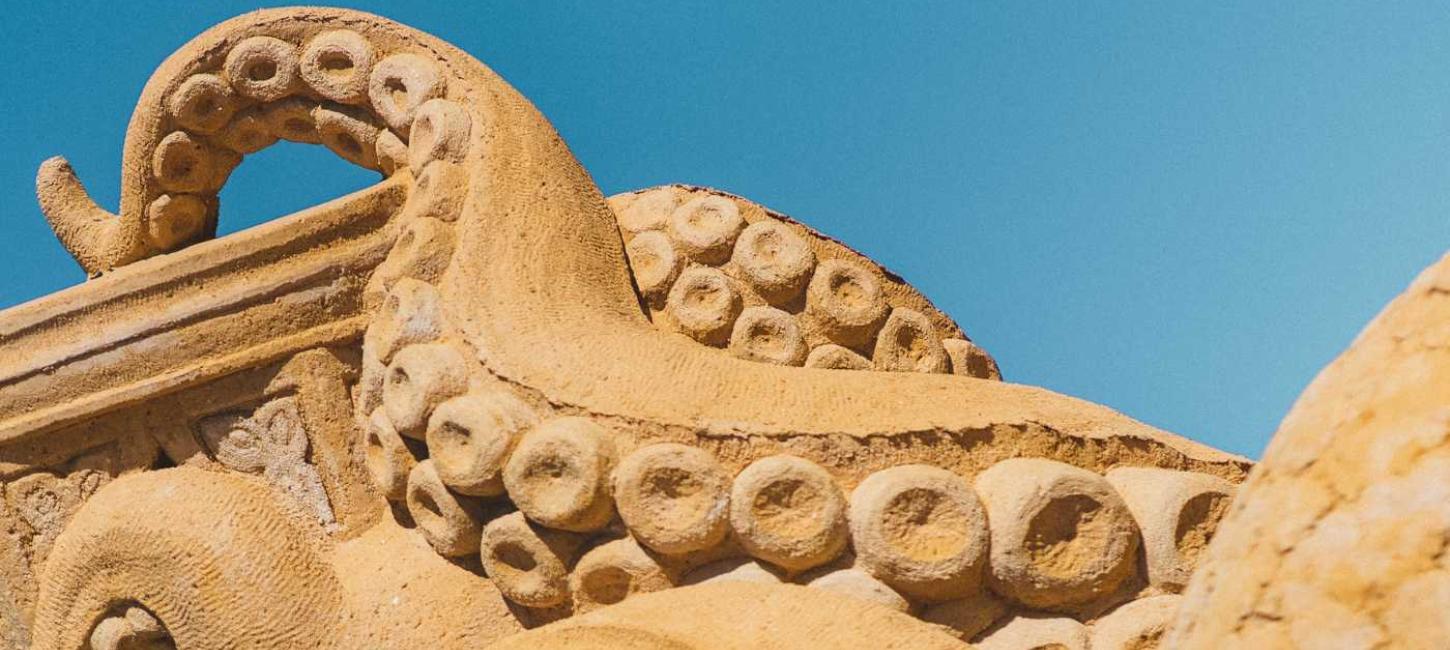 Ein Tintenfisch im Sand streckt seine Tentakel in den Himmel im Hundested Sandskulptur Park.