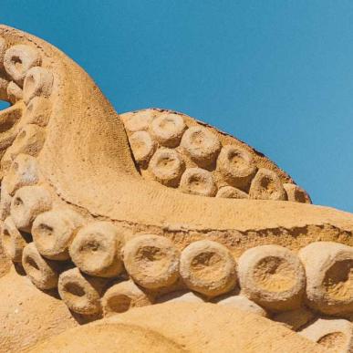 Ein Tintenfisch im Sand streckt seine Tentakel in den Himmel im Hundested Sandskulptur Park.