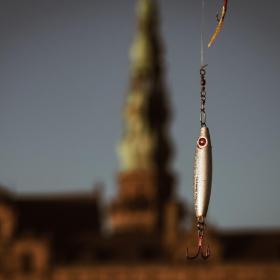 Fiskekrog i sølv holdes i luften foran Kronborg Slot.