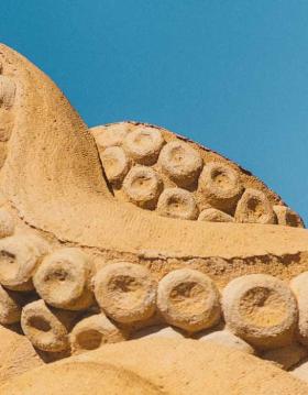 Ein Tintenfisch im Sand streckt seine Tentakel in den Himmel im Hundested Sandskulptur Park.